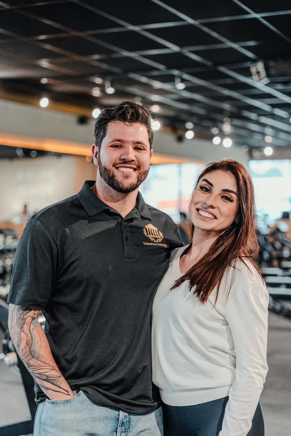 Duas pessoas sorrindo lado a lado no salão da Templo Fitness.
